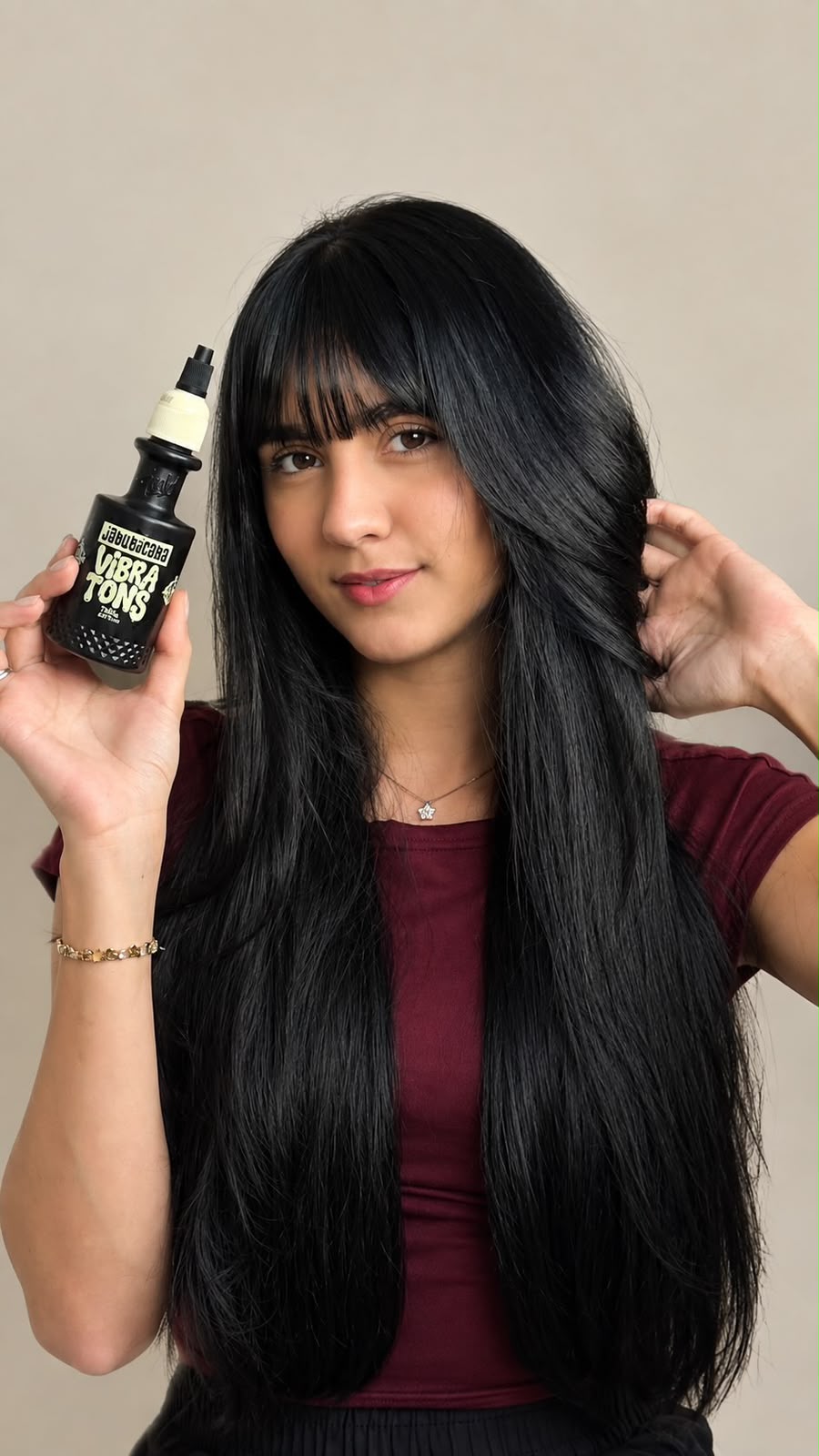 Mulher com cabelo preto longo e franja segurando Vibra Tons
